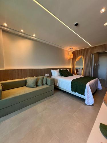 a bedroom with a bed and a couch at Novíssimo Flat Beach Class Solare - Muro Alto -Soft Open in Porto De Galinhas