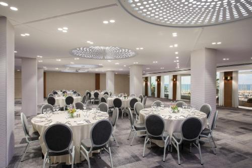 a banquet hall with white tables and chairs at Carlton Tel Aviv Hotel – Luxury on the Beach in Tel Aviv