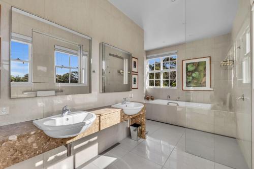 a bathroom with two sinks and a tub and a shower at Castle by the Sea - Tilba Road 26 in Bermagui