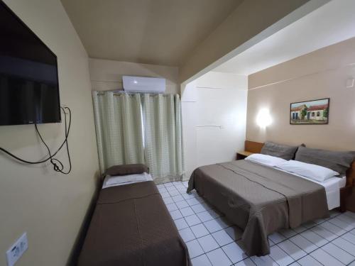 a bedroom with a bed and a flat screen tv at Ambassador Hotel in Foz do Iguaçu