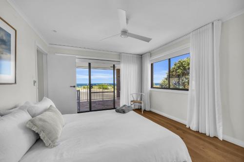 a white bedroom with a large bed and a window at Fishers - Scenic Drive 35 in Bermagui