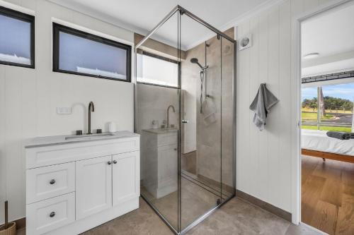 a bathroom with a shower and a sink and a mirror at Fishers - Scenic Drive 35 in Bermagui