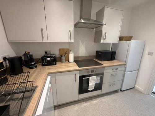 a kitchen with white cabinets and a stove top oven at Sleek 1 Bed Flat near Warwick Castle with Parking in Warwick