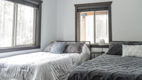 a bedroom with two beds and two windows at Polar Den Cabin in Valemount