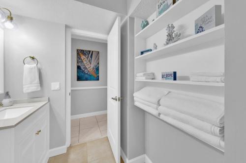 a white bathroom with a sink and white towels at Oceanfront Condo #507 at Summit Beach Resort in Panama City Beach