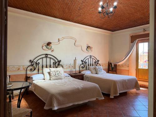 a bedroom with two beds and a chandelier at Hotel Centenario Bernal in Bernal