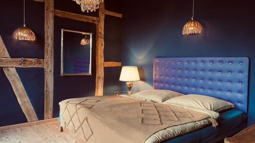 a blue bedroom with a bed with a blue headboard at Der Pfeil - Gutshaus Bückling in Rambin