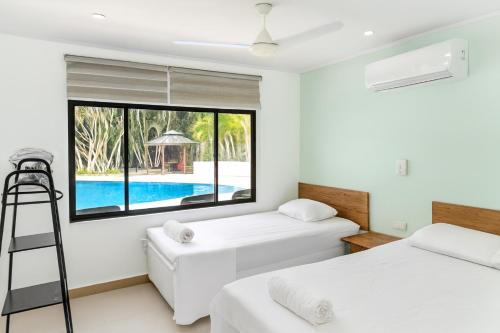 two beds in a room with a view of a pool at Quinta en Melgar piscina BBQ cerca a Piscilago in Melgar