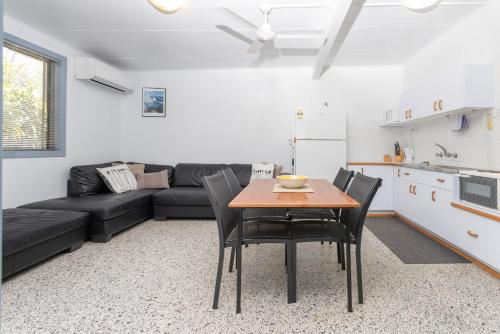 a living room with a table and a black couch at Koala Lodge Unit 3 in Iluka