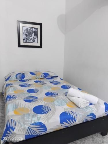 a bed with a blue and white comforter on it at Hotel Real, Villa Garzón in Villagarzón