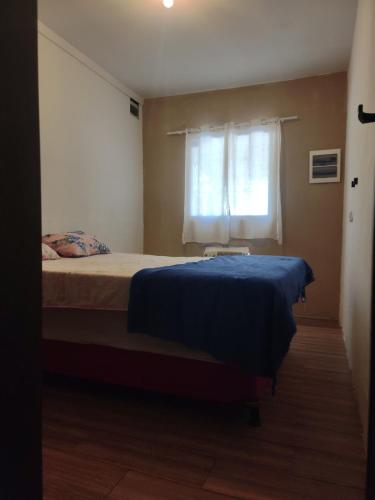 a bedroom with a bed with a blue blanket and a window at Espaço Nossa Casa, Piscina e churrasqueira Privativas in Paulista