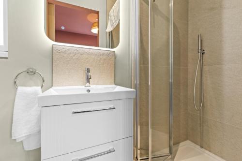 a white bathroom with a sink and a shower at Vine Cottage in Westfield