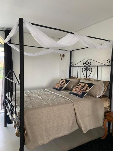 a bedroom with a black canopy bed with pillows at Caesars Castle - Hidro e Vista Cinematográfica na Mantiqueira in Pindamonhangaba