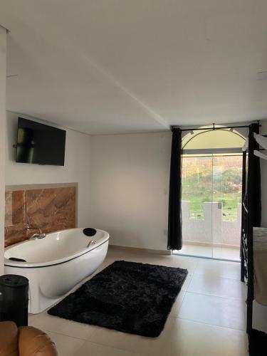 a white bath tub in a room with a window at Caesars Castle - Hidro e Vista Cinematográfica na Mantiqueira in Pindamonhangaba