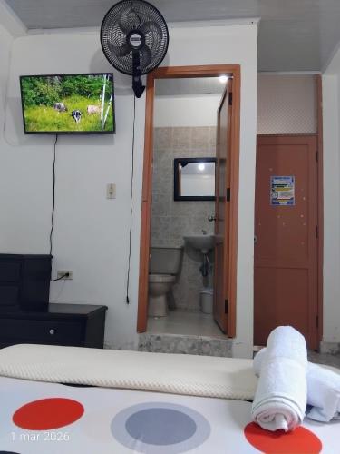 a room with a bathroom with a toilet and a television at Hotel Real, Villa Garzón in Villagarzón