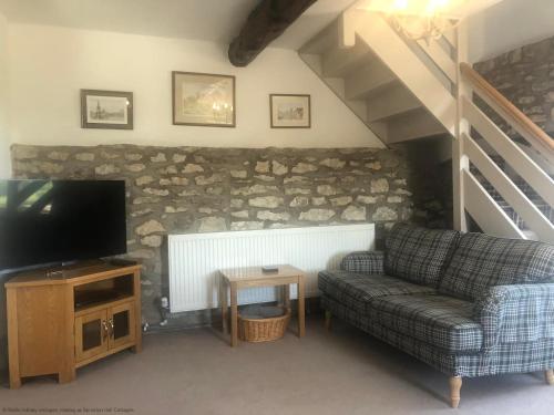 a living room with a couch and a flat screen tv at Kirkdale Cottage in Helmsley