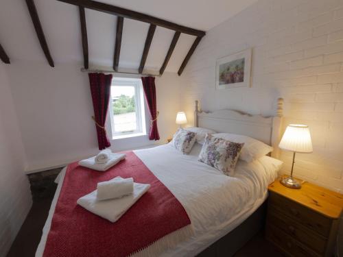 a bedroom with a large white bed with a window at Kirkdale Cottage in Helmsley