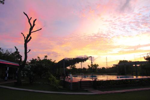a sunset over a pool in a park at Eco Hotel Black & White - Anuradhapura in Mihintale