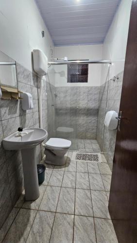 a bathroom with a toilet and a sink and a shower at Hotel Alvorada in Alegrete