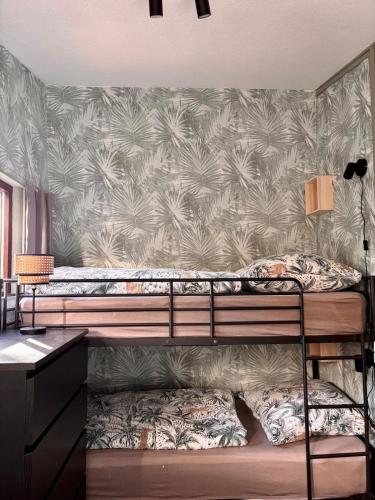 a bedroom with two bunk beds with a tropical wallpaper at Baumhausfeeling im Wald nahe der Loreley in Bogel