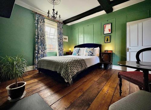 a bedroom with green walls and a bed and a table at The Corner House, Shipston-on-Stour in Shipston-on-Stour