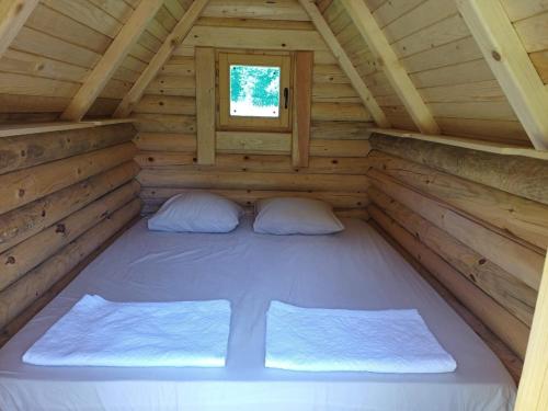 a bed in a log cabin with a window at Camp Budečevica in Žabljak