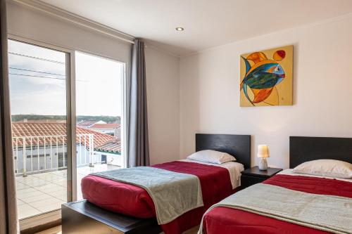 two beds in a room with a large window at Simon's Place in Ponta Delgada