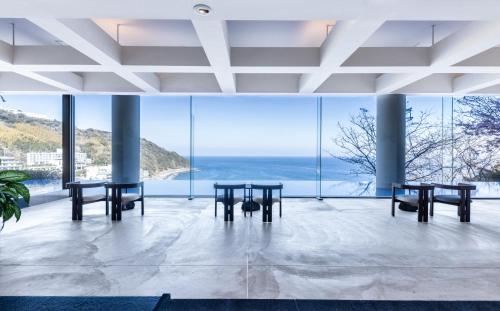 a room with tables and views of the ocean at IZU RETREAT by Onko Chishin in Higashiizu