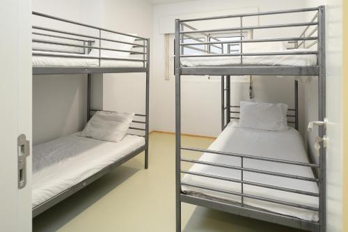 two bunk beds in a room with white walls at Help Yourself Hostels - Carcavelos Coast in Carcavelos