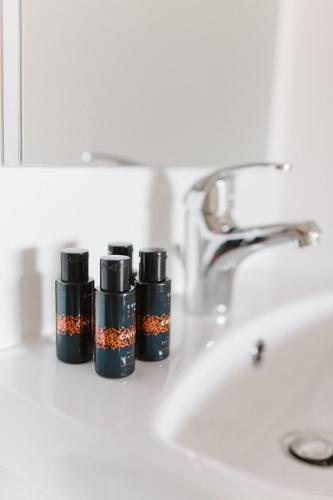 three bottles of lipstick sitting next to a sink at Ariti Luxury Apartment in Nikiana