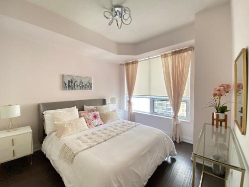 a white bedroom with a large bed and a window at Luxurious Condo Apartment with Direct Subway Access in Toronto