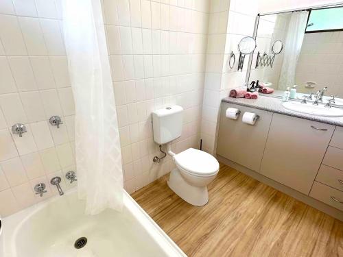 a bathroom with a toilet and a sink and a tub at Island Views in Airlie Beach