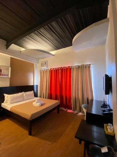 a bedroom with a bed and red curtains at First Pacific Inn Davao in Davao City