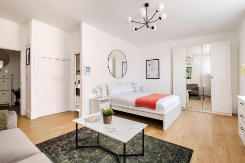 a white bedroom with a bed and a table at LONDONERS - Marylebone Serviced Apartments in London