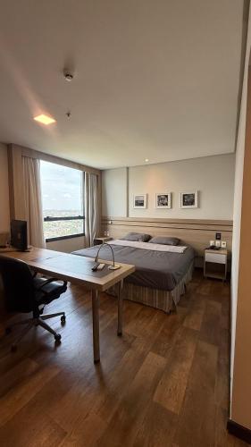 a bedroom with a bed and a desk with a desk at Flat particular no Hotel Intercity Manaus in Manaus