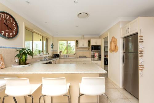 a kitchen with white appliances and a large clock on the wall at You, Me & The Sea - Walk to Mollymook Beach in Mollymook