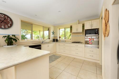 a kitchen with white cabinets and a clock on the wall at You, Me & The Sea - Walk to Mollymook Beach in Mollymook