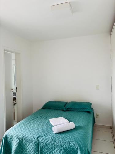 a bedroom with a green bed with two towels on it at Play Ilhotas - Centro Teresina in Teresina