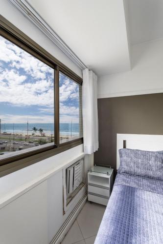 a bedroom with a bed and a large window at Caribe Carioca in Rio de Janeiro