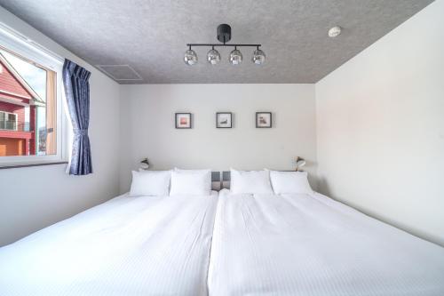 a bed with white sheets in a room with a window at Hills Niseko 106 in Niseko
