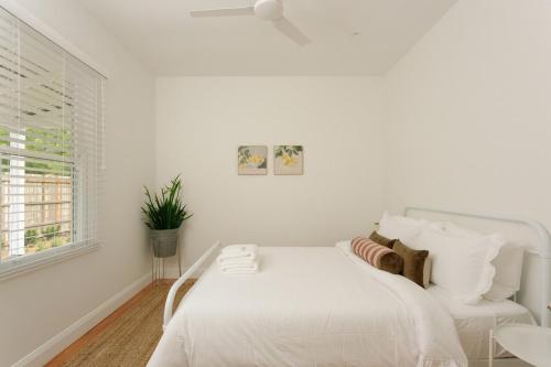 a white bedroom with a white bed and a window at Greta Cottage, Berry in Berry