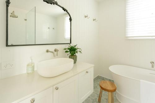 a white bathroom with a sink and a tub at Greta Cottage, Berry in Berry