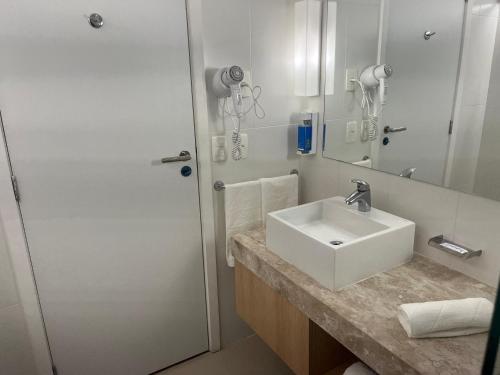a white bathroom with a sink and a shower at Stay Santos 2301 in Santos