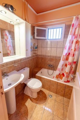 a bathroom with a toilet and a sink and a tub at Oceanfront Studio at Paramonas Beach in Paramonas