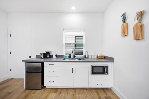 a white kitchen with a sink and a microwave at Boho-Mod Studio at East Downtown in Houston