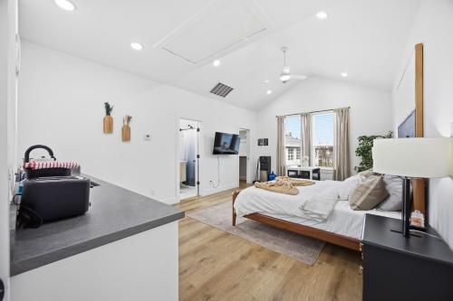 a white bedroom with a bed and a kitchen at Boho-Mod Studio at East Downtown in Houston