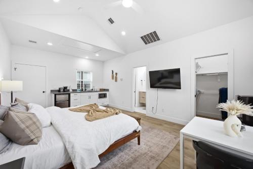 a white bedroom with a bed and a tv at Boho-Mod Studio at East Downtown in Houston