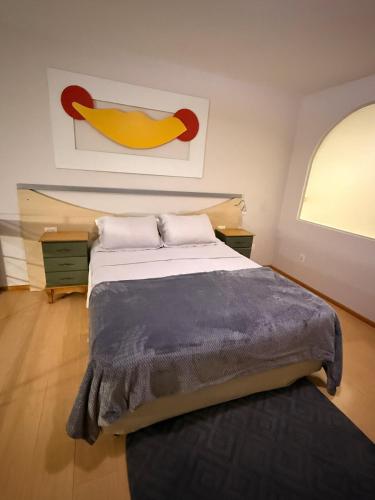 a bedroom with a large bed and a painting on the wall at Apartamento Jaragua do sul in Jaraguá do Sul