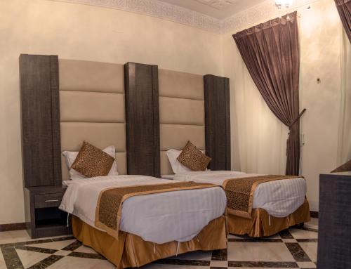 twee bedden in een hotelkamer met een groot hoofdeinde bij Rose Palace For Residential Units in Abha