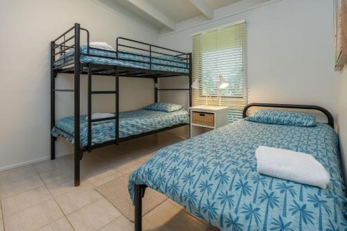a bedroom with two bunk beds and a desk at Sandpiper 11 in Smiths Lake